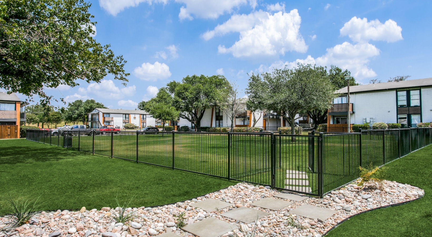 a fenced yard with grass and trees in the background at The 8500 Harwood