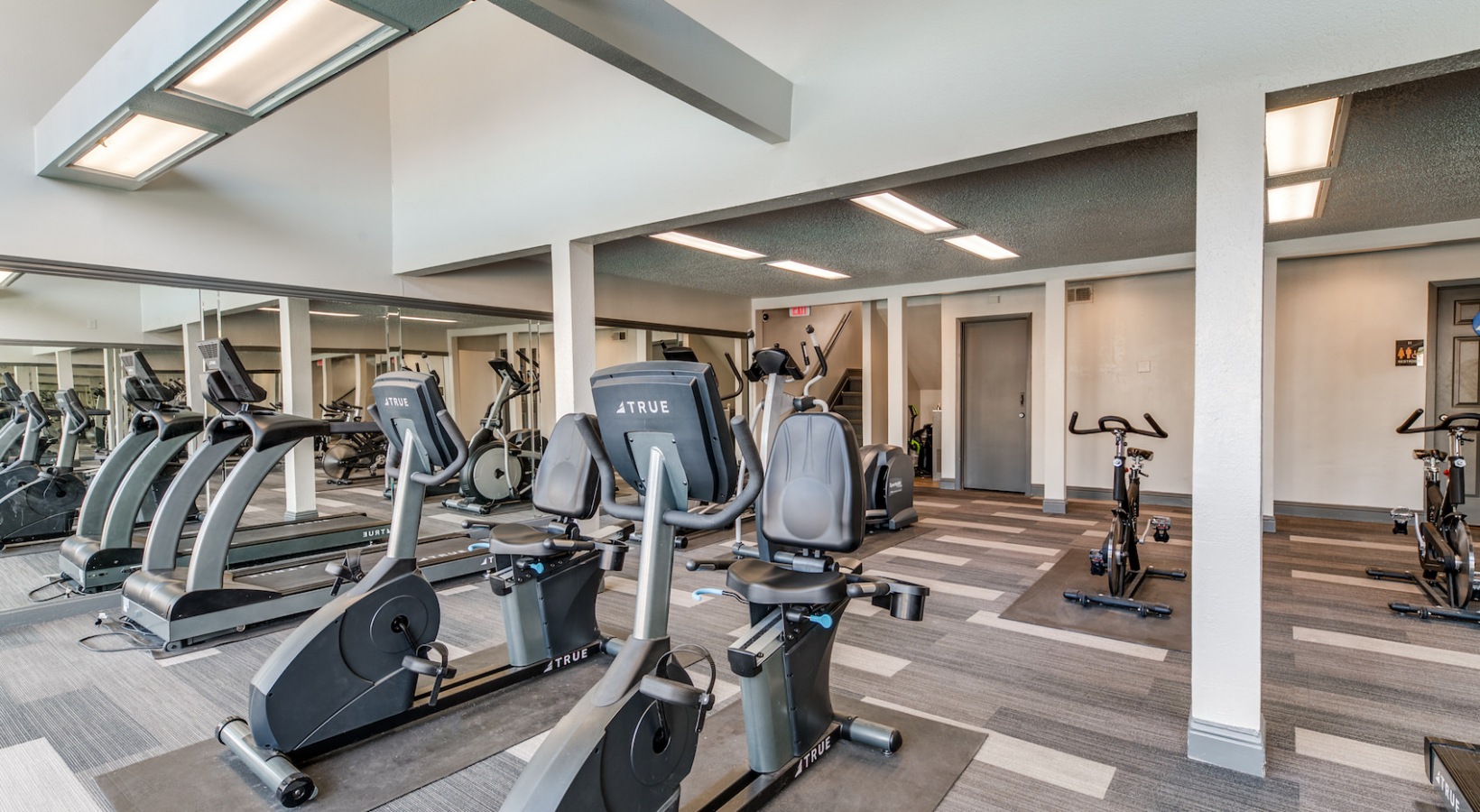 a gym room with exercise equipment and mirrors at The 8500 Harwood