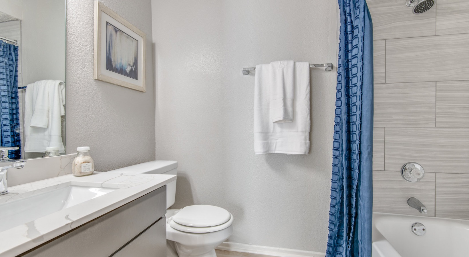 a bathroom with blue shower curtain and white toilet at The 8500 Harwood