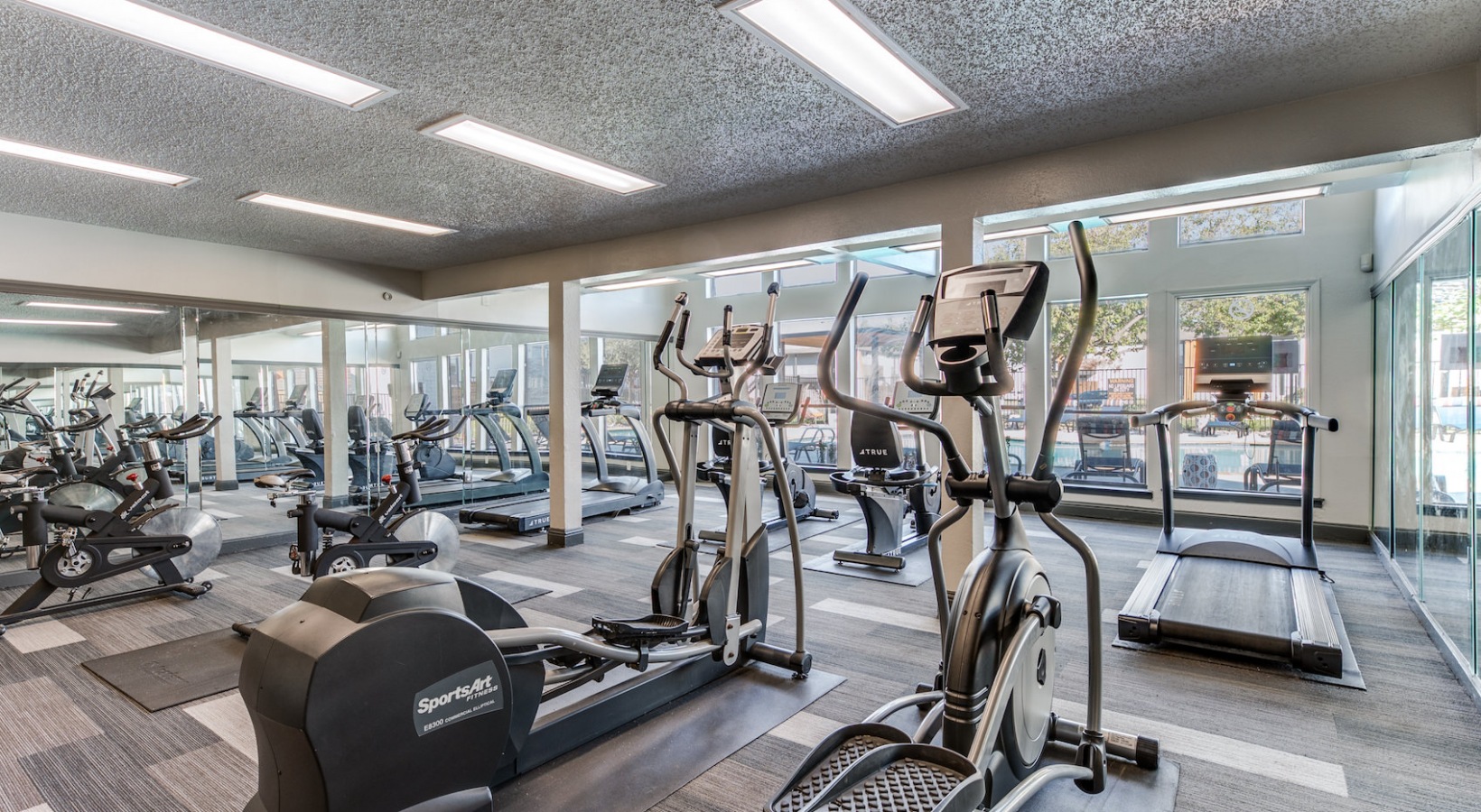 a gym room with tread machines and mirrors at The 8500 Harwood
