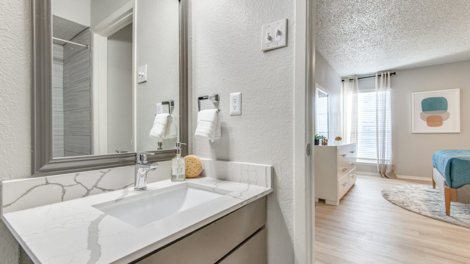 a bathroom with a sink, mirror and wood floors at The 8500 Harwood