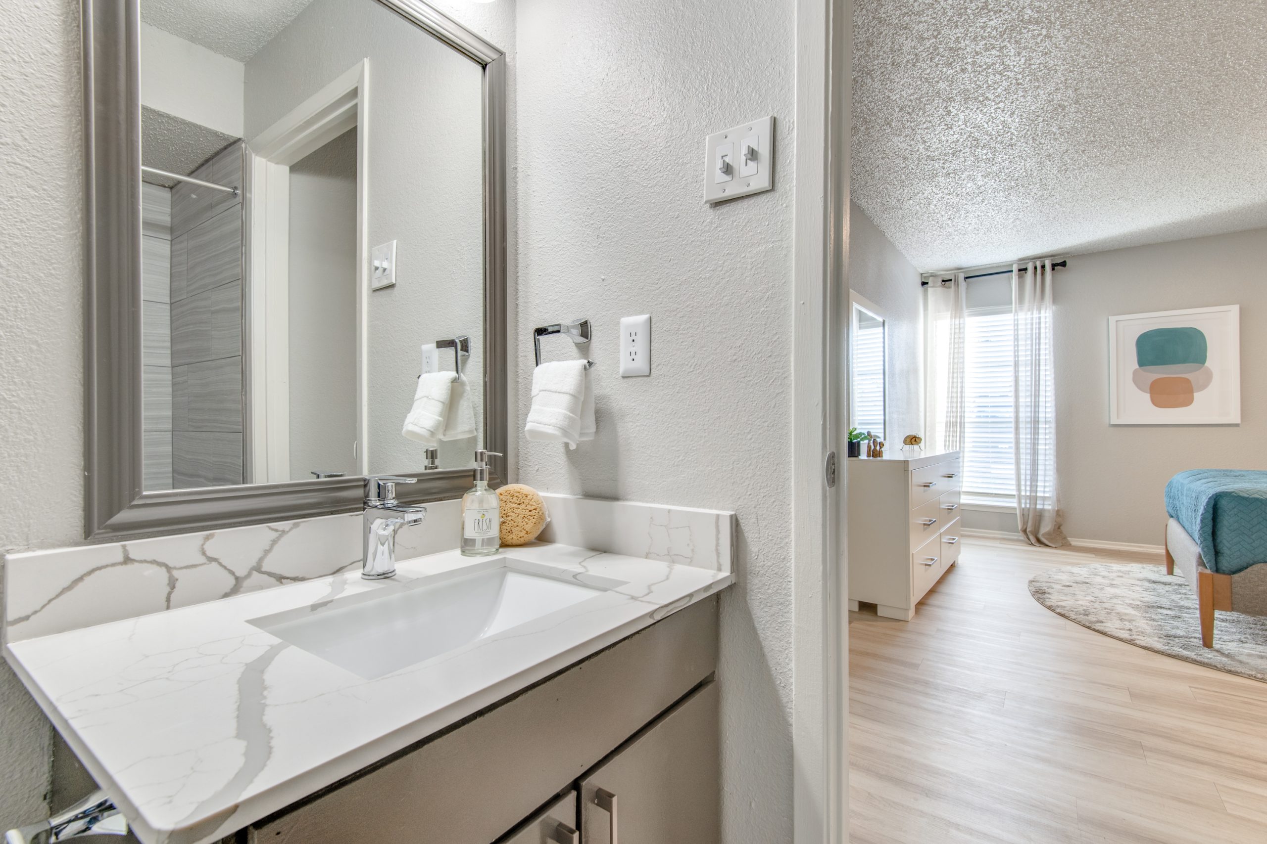 a bathroom with a sink, mirror and wood floors at The 8500 Harwood